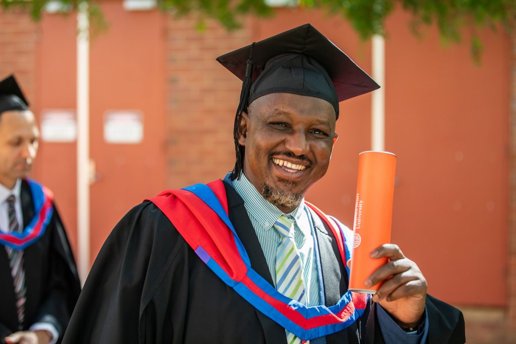 Man in gown and cap with degree