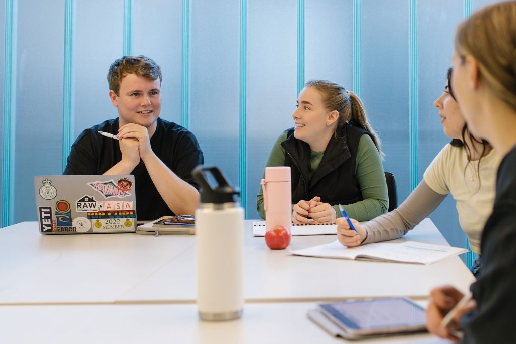 Four people sat around a table with pads and a laptop