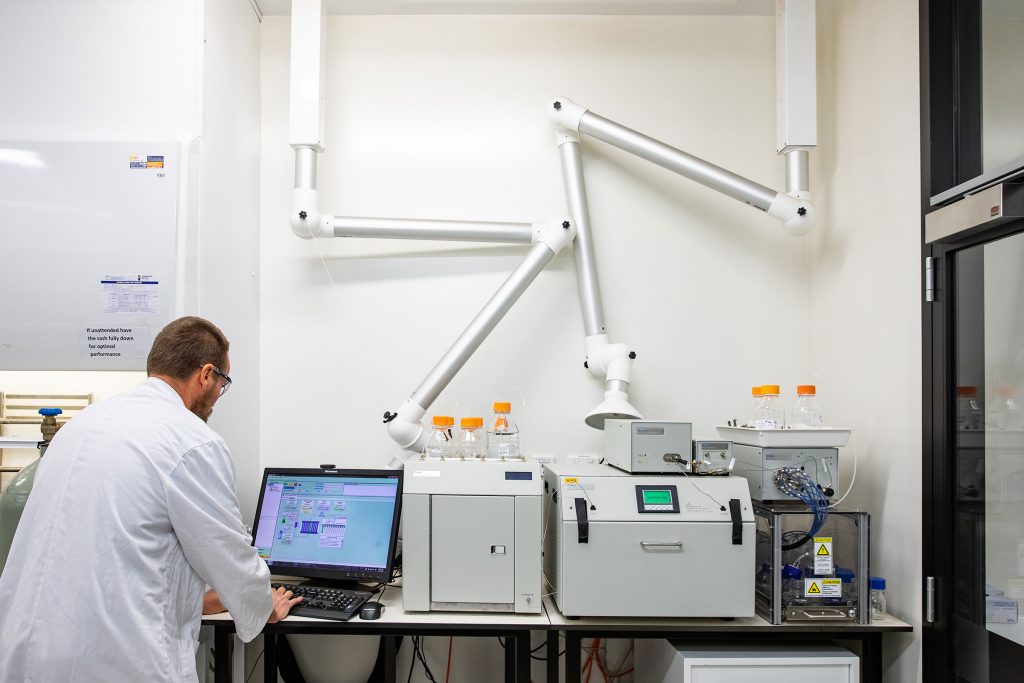 Male microbiologist looking at a computer in a lab as part of a career in microbiology