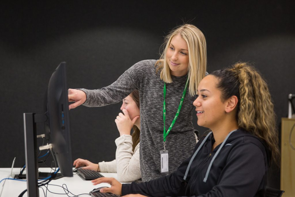 University lecturer pointing something out on a computer to a female student