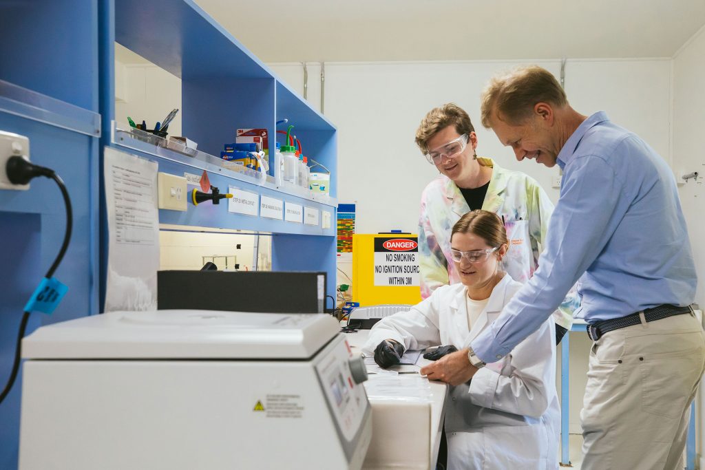 Three microbiologists looking at samples in a lab