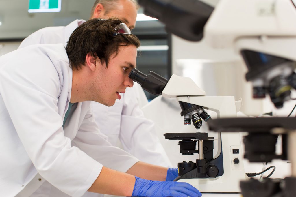Man looking into microscope in a pathology lab