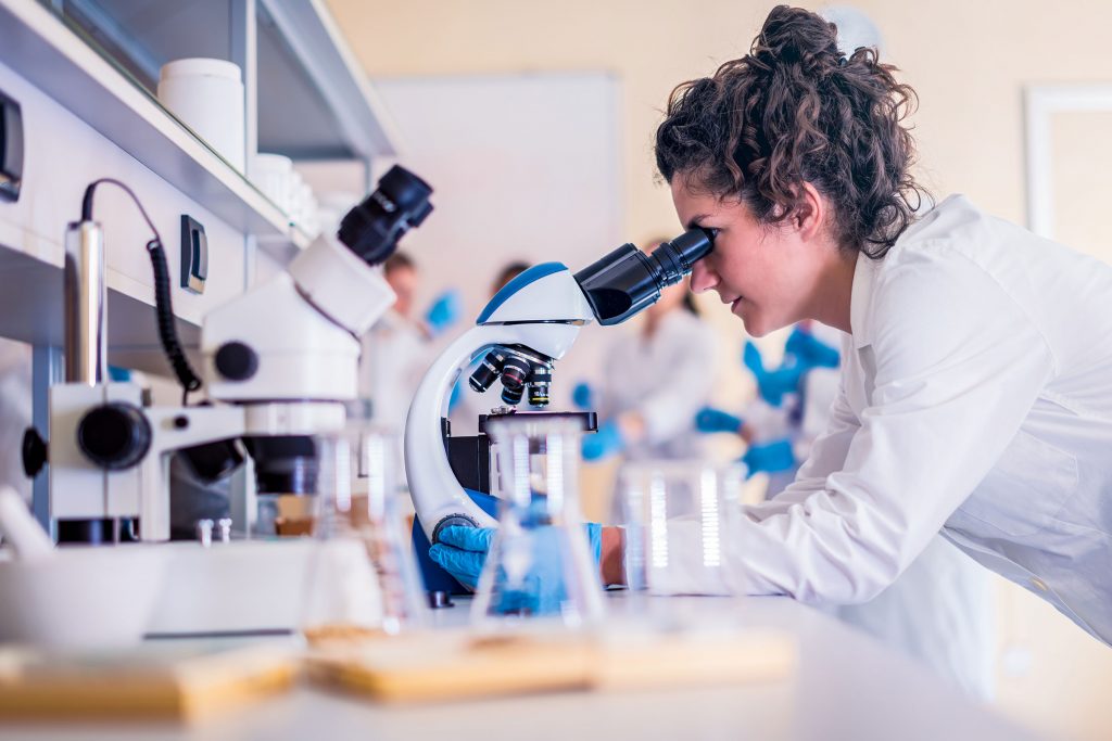 Female microbiologist looking through a microscope