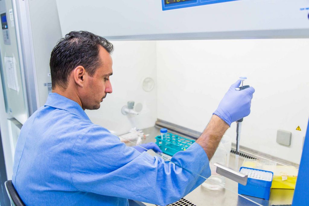 Male scientist using a pipette in a lab as part of a career in microbiology