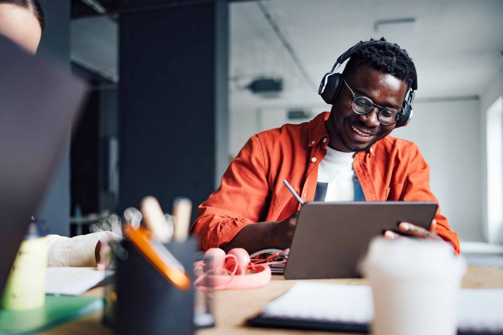 A man making a list of university student essentials on a tablet
