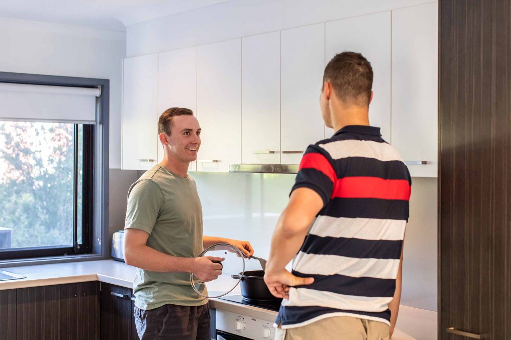 Two students cooking a meal, one of the top university student essentials