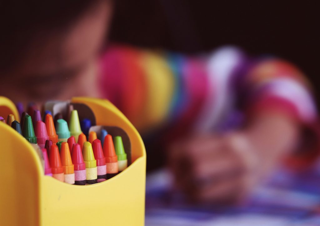 Close up of pens, with a child drawing in the background