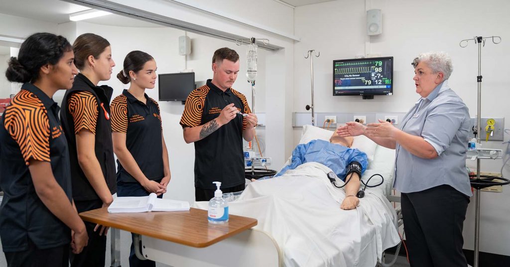 Lecturer instructing a group of students with a mannequin