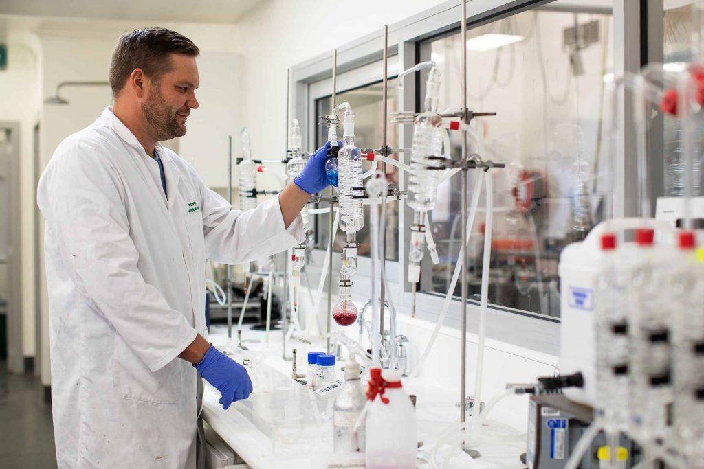 A man wearing a white lab coat, engaged in research and investigation of the scientific processes involved in production, focusing on chemistry and biology.