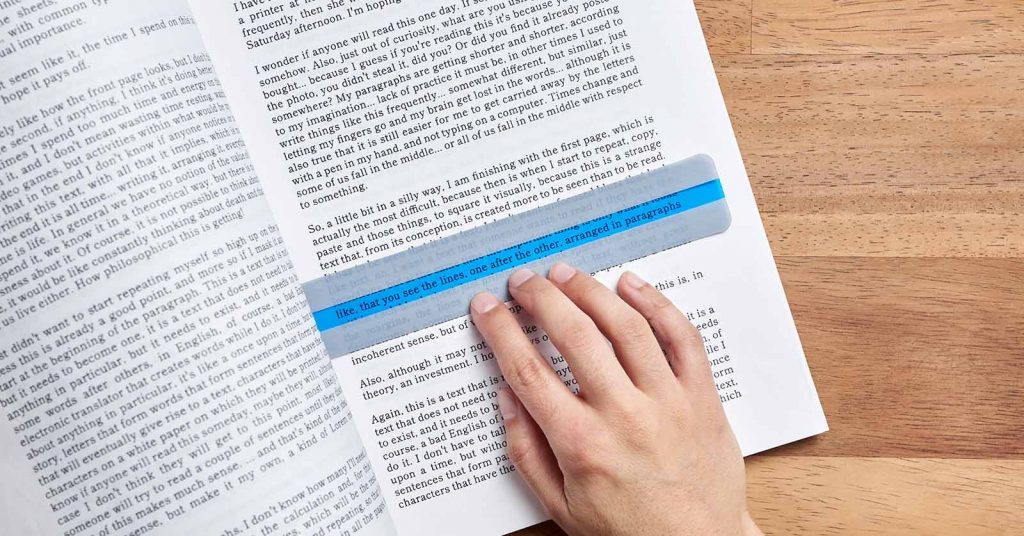 young person studying with the help of a coloured reading ruler, an educational tool that helps people with dyslexia read easier