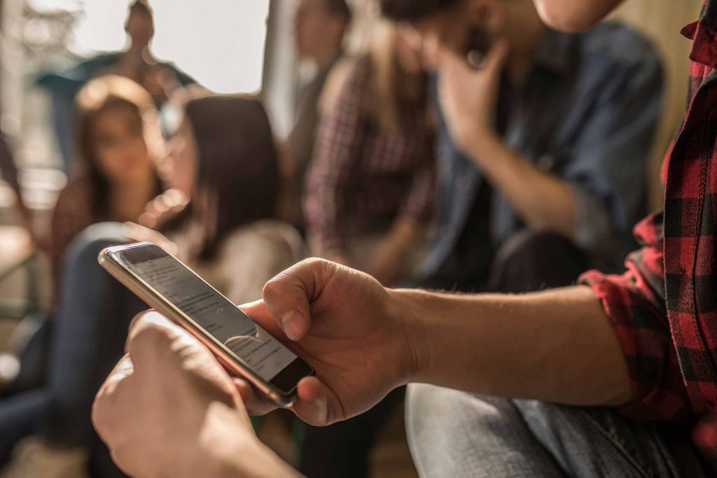 Close-up of hands holding a smartphone, with the phone's screen visible.