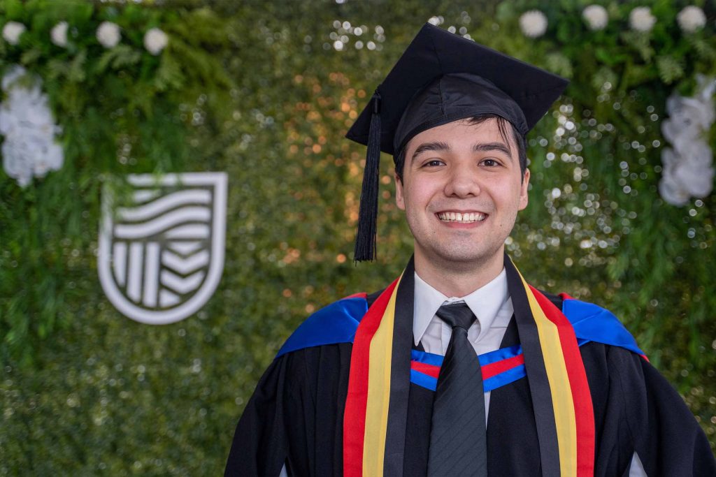 Male graduate wearing a black mortarboard and academic robe,