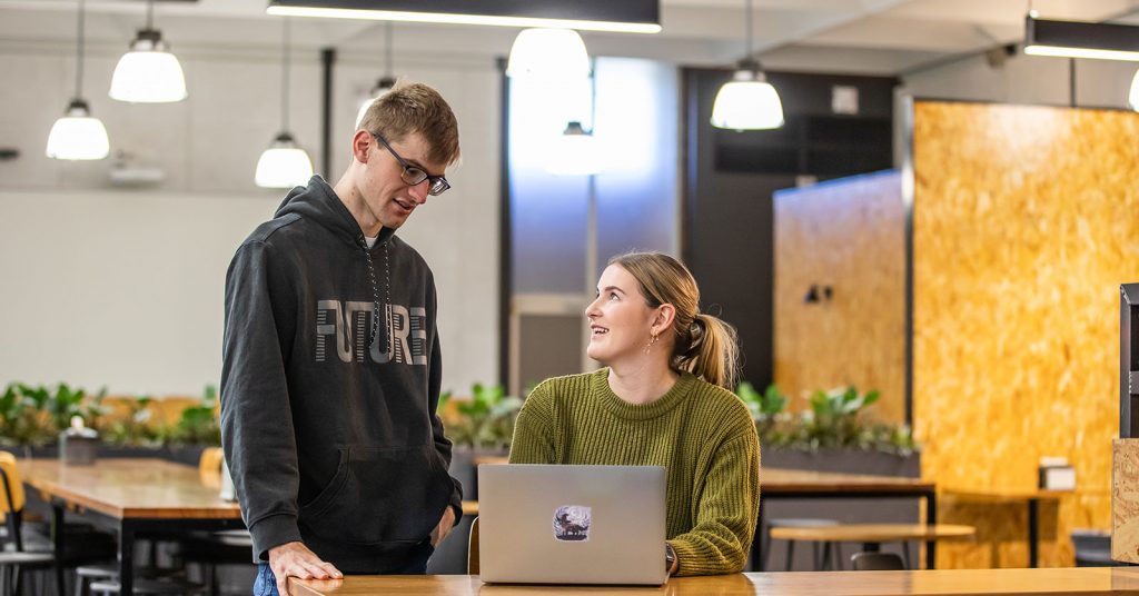 Seated woman and standing man looking at a laptop