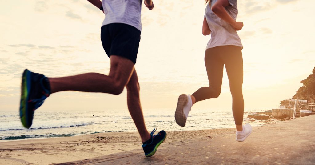 Woman and man running on the beach. Exercise is one of the top mental health tips for university students