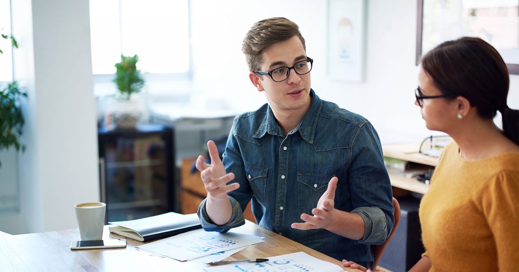 An image of two colleagues talking about the printed charts in front of them on the desk