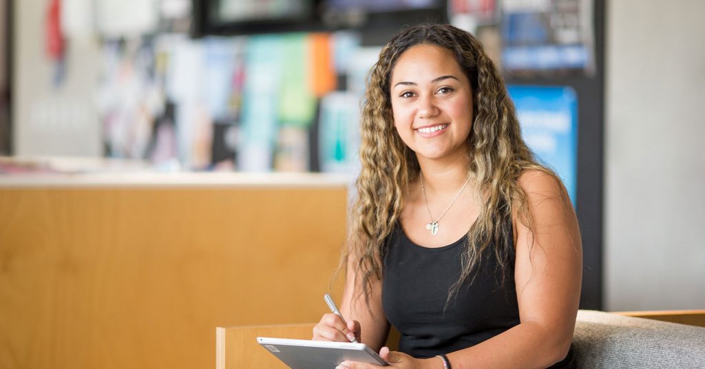 University student taking notes and smiling.