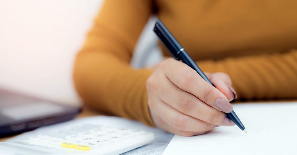woman sitting with a calculator at desk