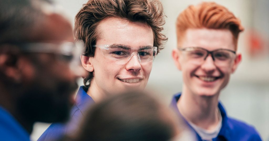 A worker standing in a group wearing safety glasses