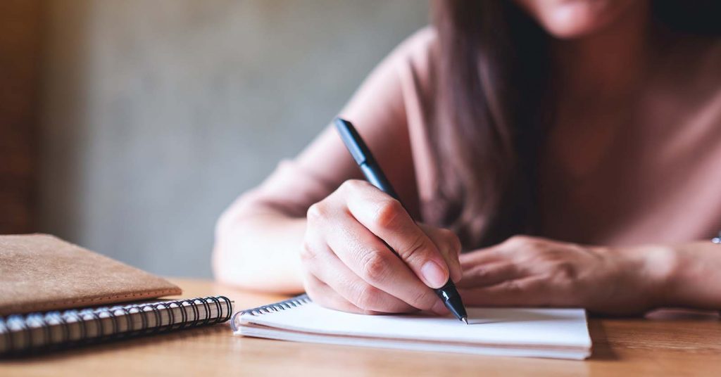 A student writing notes in a notebook