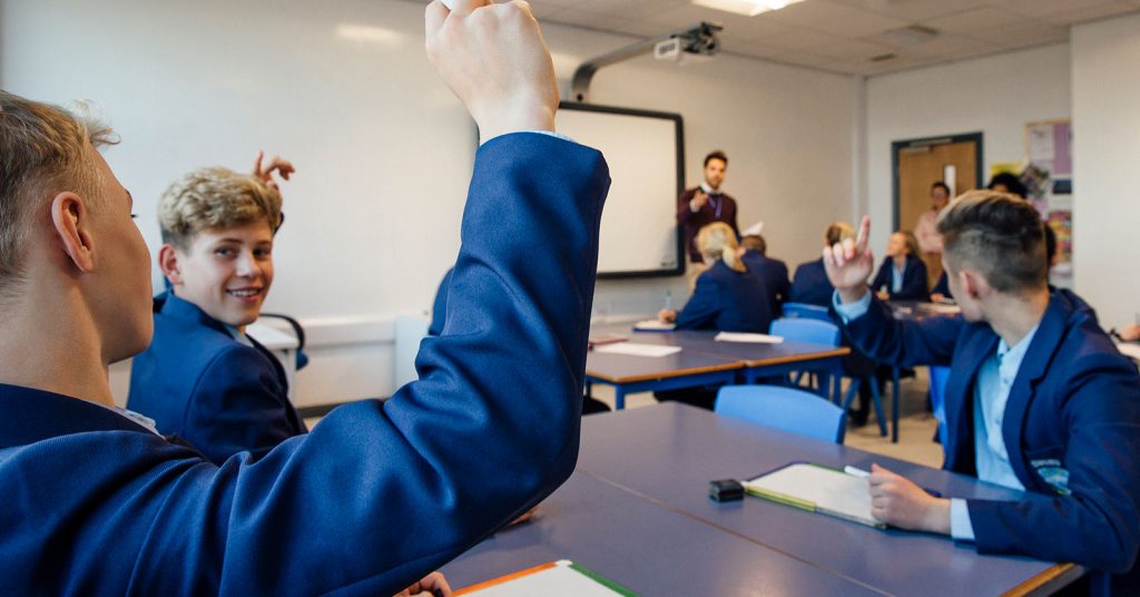 A student raising their hand during a class discussion.