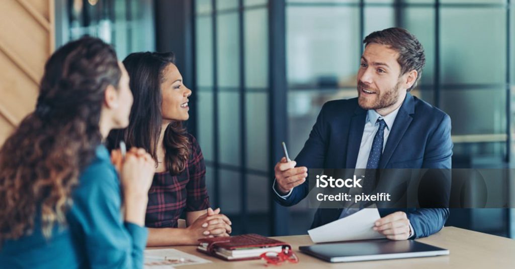 two women talking to man at desk