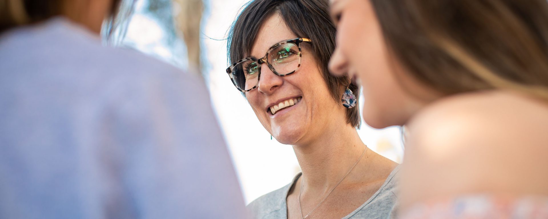 Photo of a woman smiling, surrounded by friends