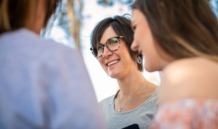 Photo of a woman smiling, surrounded by friends
