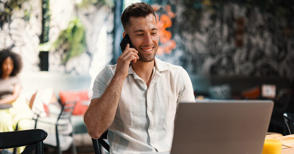 man mobile phone while working on laptop