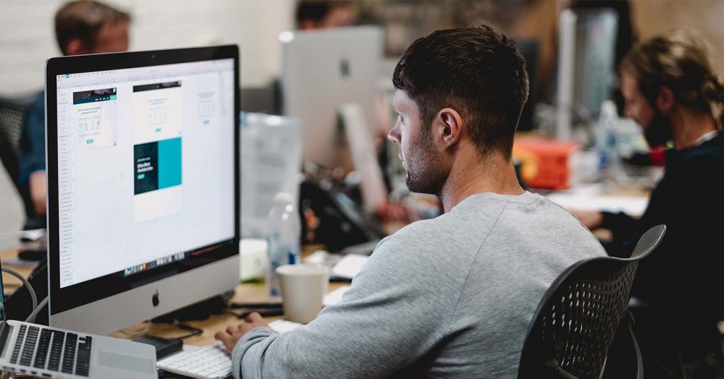 A man uses a Mac to design a marketing campaign