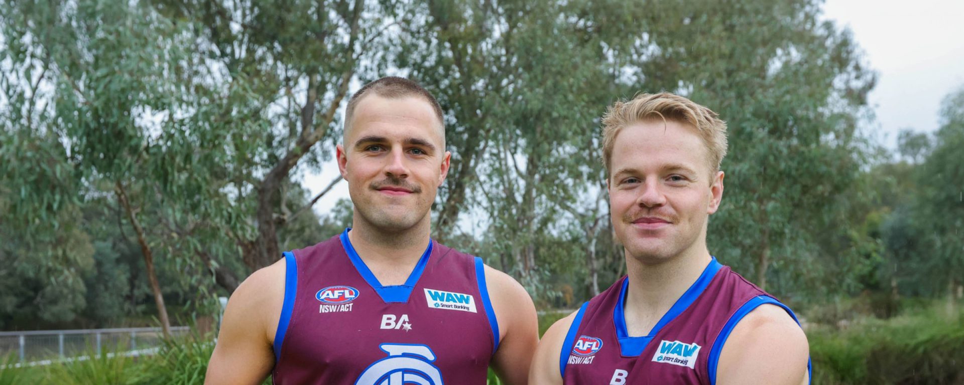 Oscar Cameron holding an AFL football, alongside another footballer mate