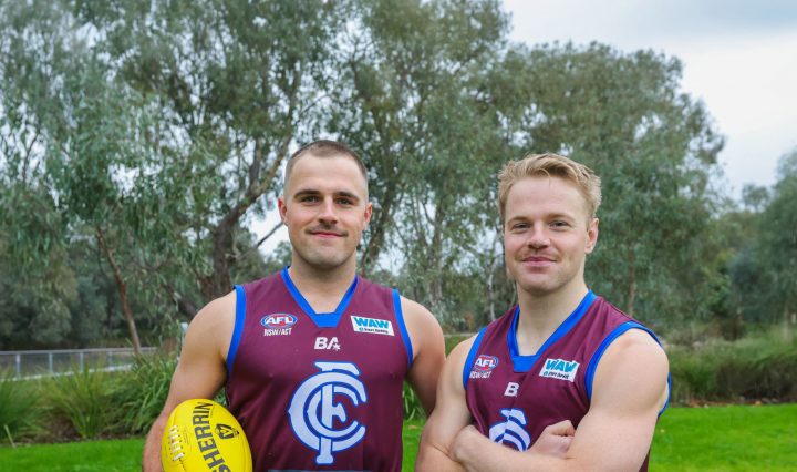 Oscar Cameron holding an AFL football, alongside another footballer mate